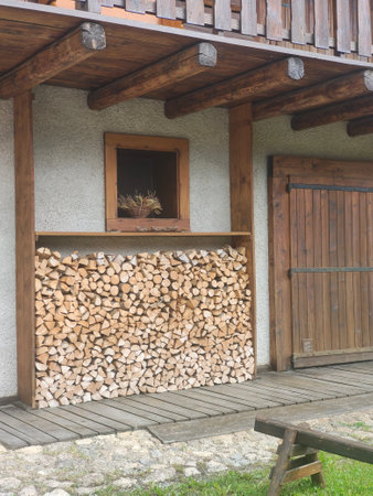 Firewood stacked in front of a wooden house with a window.