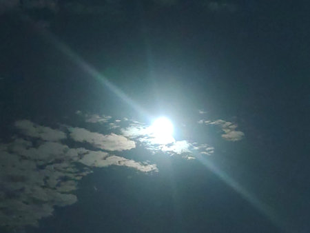 The sun shines through the clouds in the blue sky in the evening