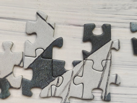 Jigsaw puzzle pieces on white wooden background, closeup of photoの写真素材