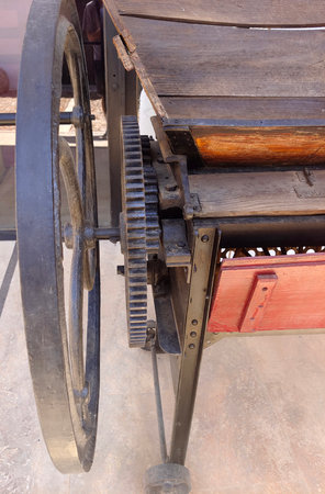 Vintage machinery with wooden and metal components, featuring a large wheel and gear system