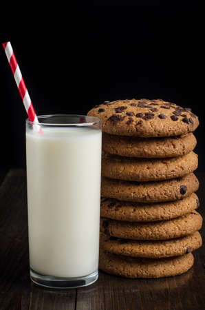 Glass of milk on wooden table with cookies