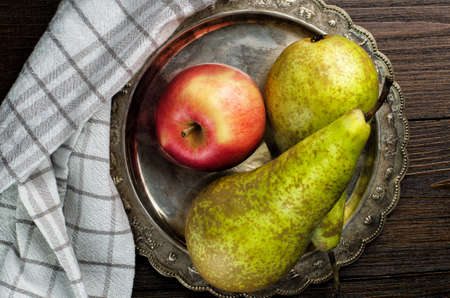 pears and apple, vintage plate with napkin on wooden background, top viewの写真素材