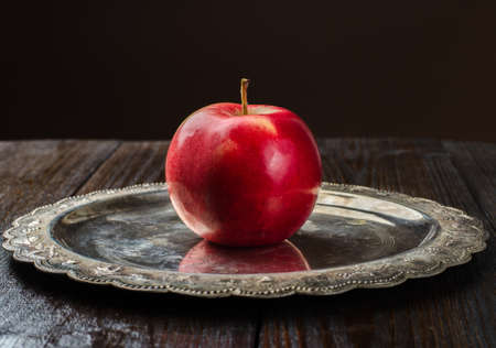 Red apple, vintage plate on wooden background, front viewの写真素材
