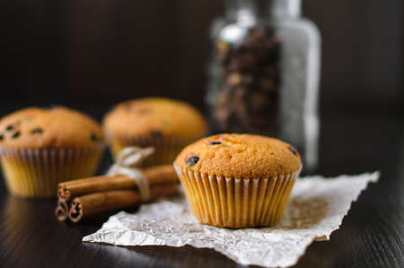 Closeup muffins with coffee jar and cinnamon on dark background
