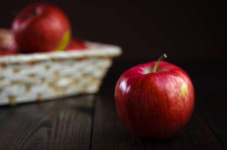 Red apples in a basket on wooden background