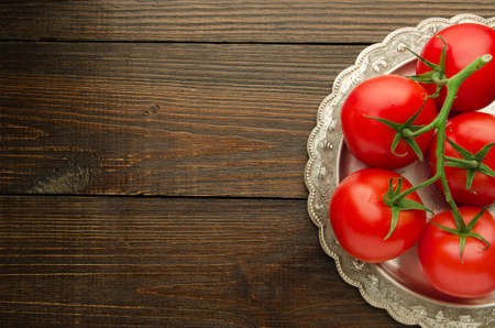 tomatoes on vintage plate top view, wooden backgroundの写真素材
