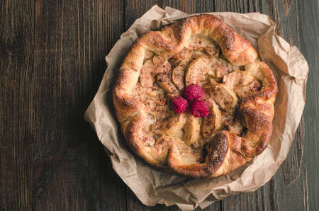 Apple pie with cinnamon and raspberry on a wooden backgroundの写真素材