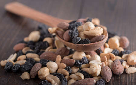 Dried fruits with nuts and raisins in a wooden spoon. Wooden background.の写真素材