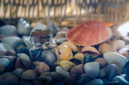 Shells in a glass jar on pebble beach .の写真素材