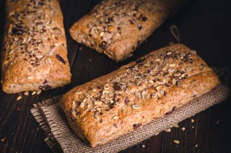 Healthy bread on burlap. Homemade whole grain fitness bread sprinkled with seeds. Front view.の写真素材