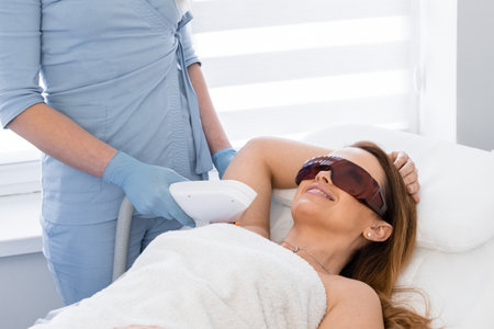 Laser hair removal procedure in a cosmetology beauty salon. Woman cosmetologist removes body hair.の写真素材