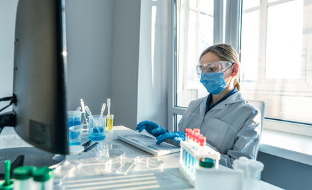 A scientist who focuses on a computer in a medical laboratory. The photograph shows a medical scientist entering data into a computer in a chemical laboratory.の写真素材