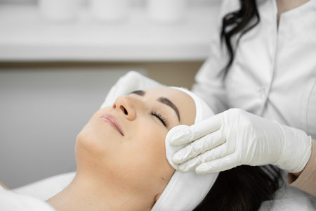 The first steps to perfection: the beautician prepares the skin of a womans face for cosmetic procedures with cotton pads, cleansing and raising skin health.の写真素材