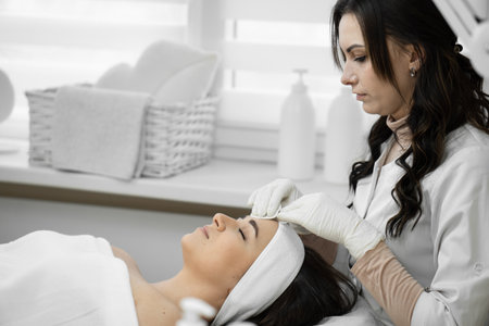 Professional care: cosmetology at a high level, when a qualified specialist cleanses the skin and provides comprehensive care for the appearance of a woman in a beauty clinicの写真素材
