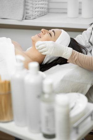 A young woman receives luxurious care from a cosmetologist who cleanses the skin, providing an individual approach and promoting rejuvenation in the beauty salon, relaxing and restの写真素材