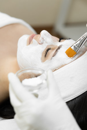 A touch of beauty: this photo shows how a cosmetic mask creates a soft and gentle touch of beauty on the skin, making it more attractive and healthy. Woman in beauty clinic at spa treatmentの写真素材