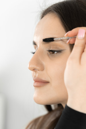 Photo attentiveness and professionalism cosmetologist who performs eyebrow correction procedure....