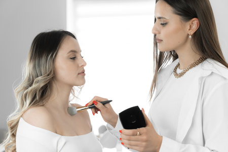 The makeup artist uses his creativity and skills to create a unique makeup that emphasizes the best features young womans face, neck and chest and emphasizes her style. White color in beauty salonの写真素材