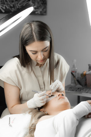 The photo shows eyelash extension process, where the beautician carefully works with each eyelash, giving them a natural look and length. Beauty treatment, relaxation and relaxation in beauty salonの写真素材