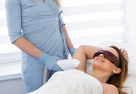 Cosmetology session of laser hair removal at a meeting with beauty. The womans body shone with new brilliance thanks to a visit to a beauty clinic. The work of a professional cosmetologistの写真素材