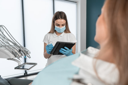 The patient provides the dentist with complete information about his complaints about dental health. The patient learns about the recommended treatment plan and possible methods of correcting the condition of the teeth. The dentist fills out the patients medical record with all the necessary information.の写真素材