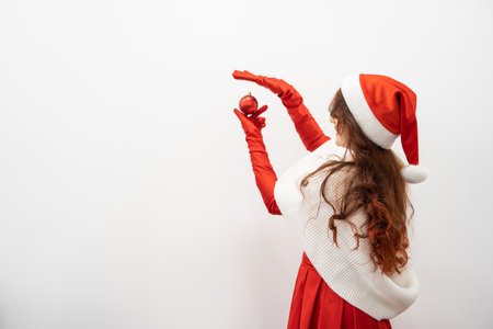 A beautiful Christmas ball held by a woman in her hand creates a festive charm and attraction to celebrate Christmas and New Year during the winter holidays. Festive decor in redの写真素材