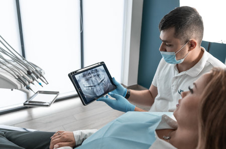 The dentist carefully examines the condition of the patients oral cavity on CT and MRI images and develops an individual treatment plan. A modern medical center provides high quality treatment and helps to restore the health of the patients teeth and smile.の写真素材