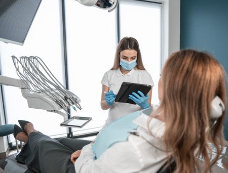 The patient receives professional advice on oral care. The dentist discusses possible alternative treatments for the patient. The patient feels comfortable and confident in the dental clinic.の写真素材