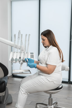 Modern equipment is visible in the background, which indicates the high professional level of the doctor and her willingness to provide the best dental care. With stylish design and expressions of care, the dentist strives to create a pleasant environment for her clients.の写真素材