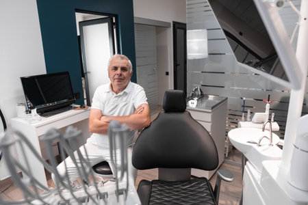 An experienced dentist, sitting at the dental chair, prepares for a basic dental examination, striving to ensure maximum comfort and effectiveness of treatment.の写真素材