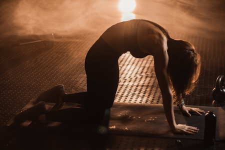 A woman in a vibrant fitness scene shows intense focus during her workout. Her determination and balance are crucial for optimal health, highlighting mindfulness and motivation in exerciseの写真素材