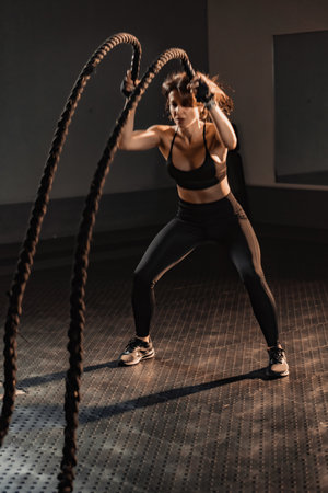 Engaging in a Dynamic Workout with Battle Ropes set in a Contemporary Gym Environment for an energized fitness experience. Ideal for those dedicating themselves to achieving optimal healthの写真素材