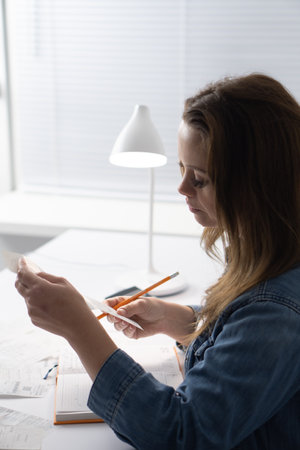 In a minimalistic and wellorganized workspace designed to enhance focus and creativity, a dedicated woman diligently reviews her notes, boosting her productivity and fostering effective organizationの写真素材