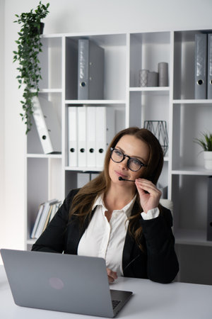 A Thoughtful Businesswoman Engaged in Work at Her Laptop Within a Modern Office Setting, Reflecting a Professional Atmosphere and Contemporary Design Elements That Inspire Creativity and Focusの写真素材