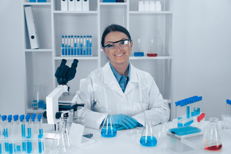 A dedicated scientist is currently working in a laboratory, surrounded by an array of glassware and microscopes, fully engaged in innovative research and experiments to further the field of scienceの写真素材