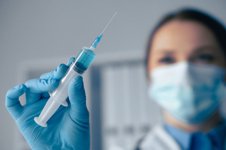 A healthcare professional is holding a syringe, preparing to administer a vaccination. This important act ensures the health and safety of patients, particularly in clinical and hospital settingsの写真素材