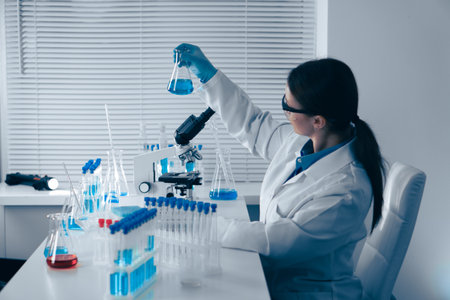 Engaging in Laboratory Research involves the use of glassware and a microscope, as well as various scientific techniques and protocols essential for accurate analysis in the field of biochemistryの写真素材