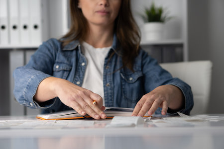 In a modern workspace, a woman focuses on analyzing notes at her desk, showcasing concentration, creativity, and productivity as she writes and reflects on her ideas professionallyの写真素材