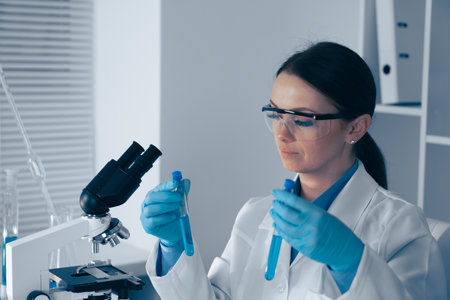 A dedicated laboratory professional is meticulously analyzing test tubes under a microscope,...