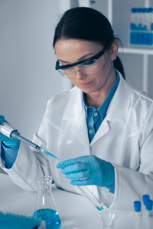 A Female Scientist is actively conducting a detailed laboratory experiment while skillfully using a pipette, showcasing her expertise in the fields of biotechnology and chemistry, among othersの写真素材