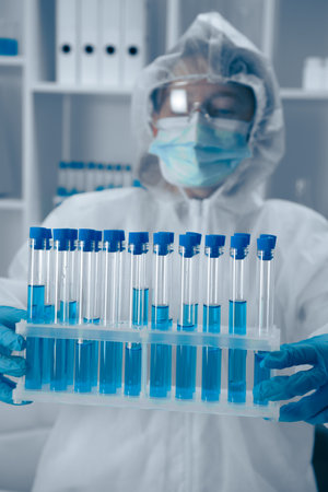 A Laboratory Technician skillfully analyzing a variety of test tubes filled with vibrant blue solutions, contributing to critical research in the fields of biotechnology and healthcareの写真素材