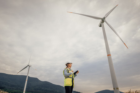 A Wind Energy Technician monitors turbine efficiency at a Renewable Energy Farm, ensuring optimal performance to harness natures power for sustainable energy and promote an ecofriendly futureの写真素材