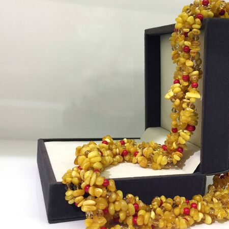 Amber beads hang from the open lid of a brown jewelry box.の写真素材