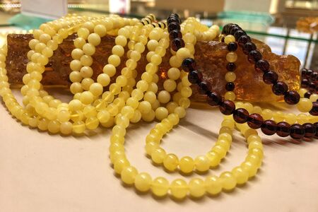 A lot of Baltic amber white beads lie on a piece amber.の写真素材