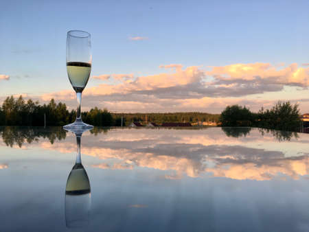 A glass of wine reflected in the mirror surface of the tableの写真素材