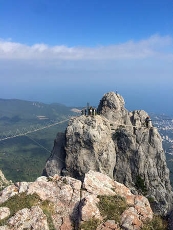 A man walks across a loose rope bridge stretched between two mountain peaks. Extreme entertainment for tourists on Mount Ai-Petri in Yalta.の写真素材