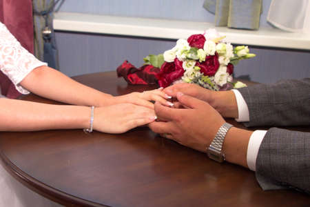 the newlyweds hold hands while sitting at the tableの写真素材