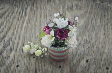artificial flowers in vase on wooden plateの写真素材