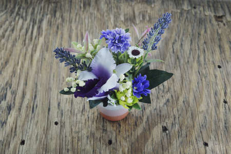 artificial flowers in vase on wooden plateの写真素材