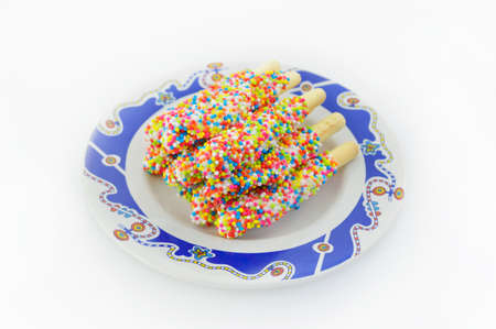 biscuit stick coated with rainbow on dishの写真素材